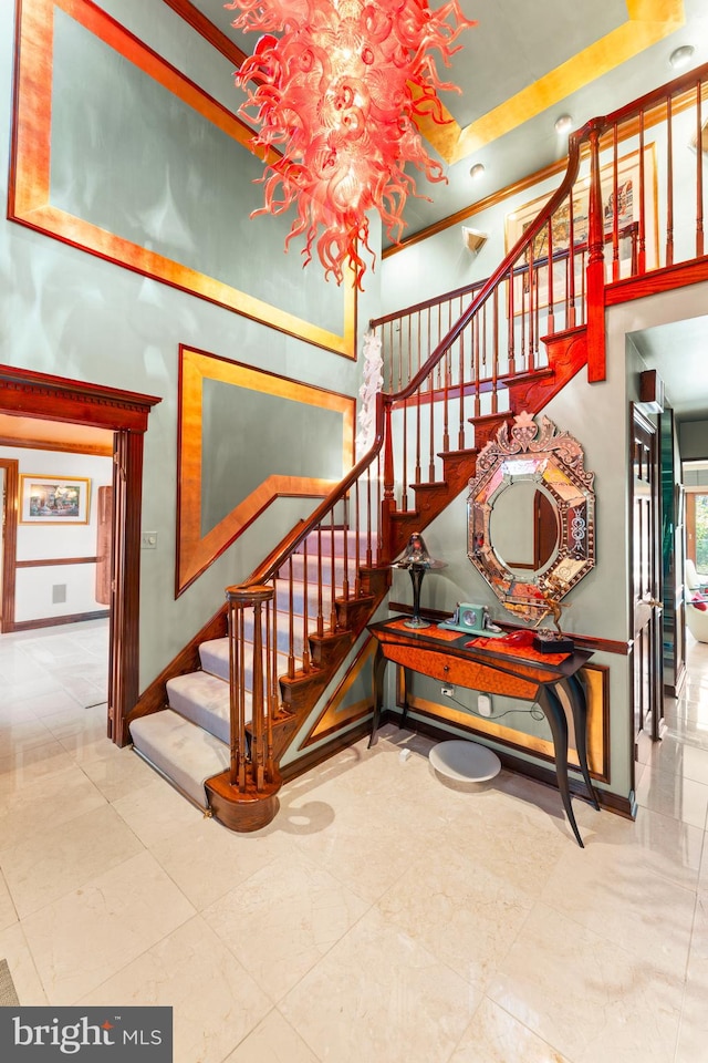 stairway featuring ornamental molding and an inviting chandelier