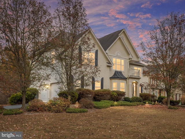 view of front of home featuring a garage, a lawn, and a balcony