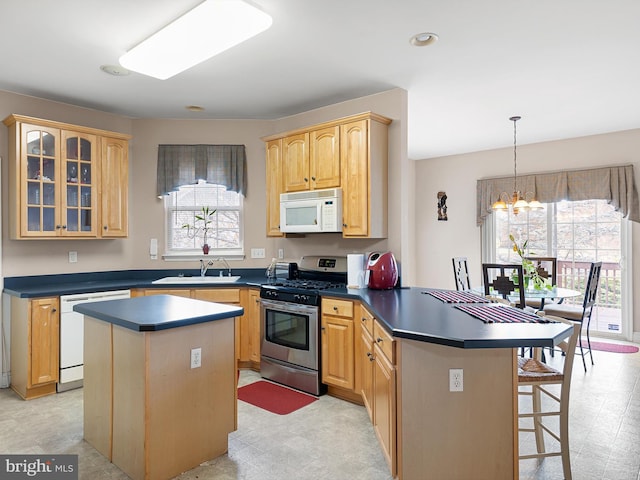 kitchen featuring hanging light fixtures, a center island, white appliances, and sink