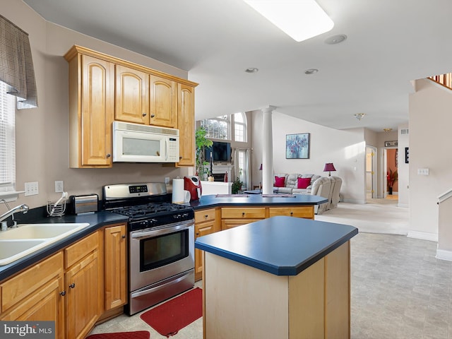 kitchen featuring stainless steel gas stove, ornate columns, sink, kitchen peninsula, and a center island