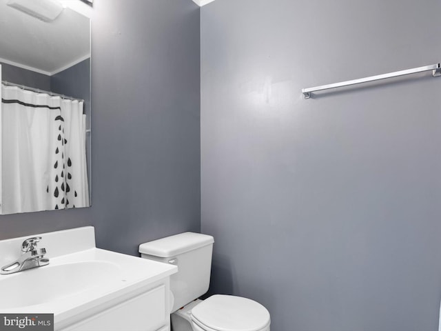 bathroom featuring toilet, vanity, and ornamental molding