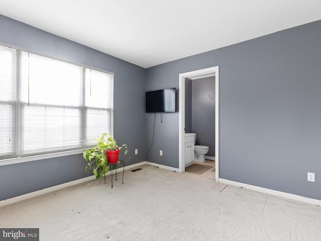 interior space featuring light colored carpet and ensuite bath