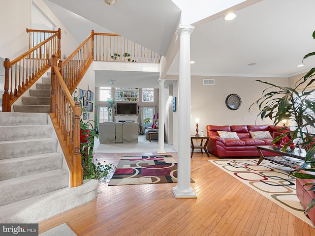 living room with wood-type flooring, ornate columns, and ornamental molding