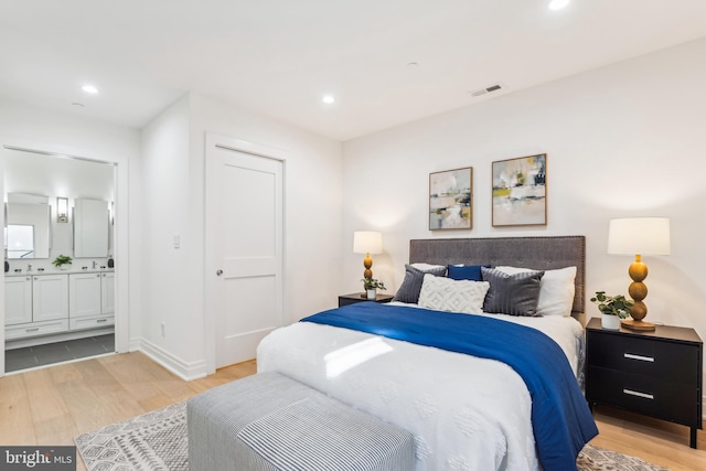 bedroom with ensuite bath and light hardwood / wood-style flooring