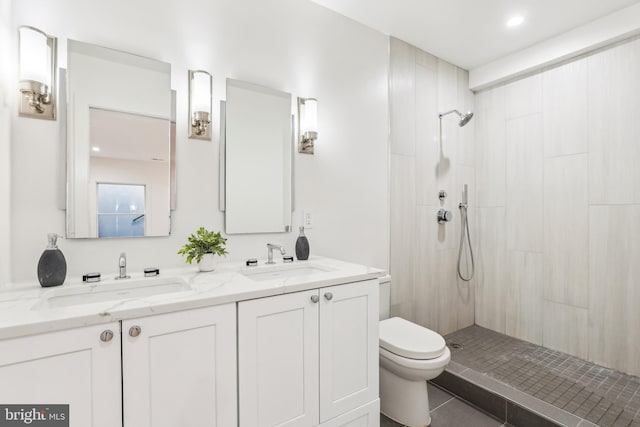 bathroom with a tile shower, tile patterned flooring, vanity, and toilet