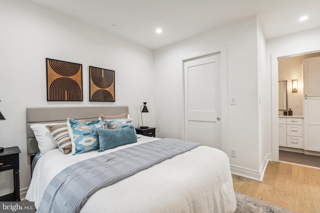 bedroom featuring light wood-type flooring and ensuite bath