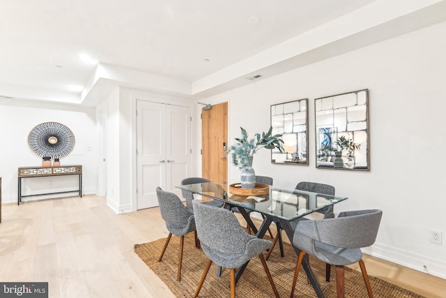 dining area featuring light hardwood / wood-style flooring and a tray ceiling