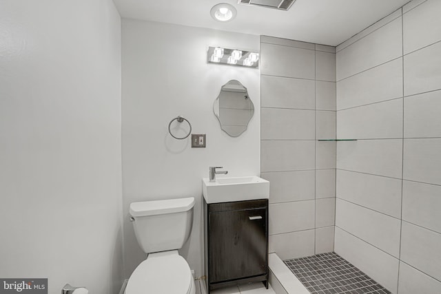 bathroom featuring vanity, toilet, and a tile shower