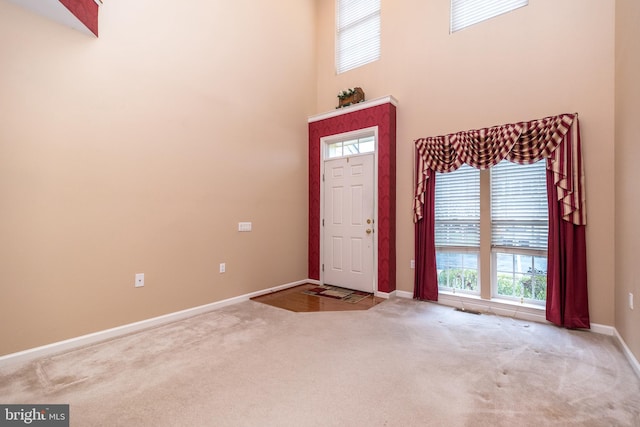 carpeted foyer entrance with a towering ceiling