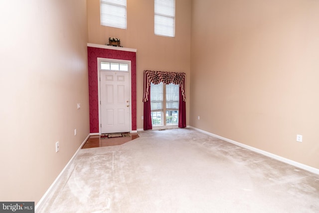 carpeted foyer entrance featuring a towering ceiling