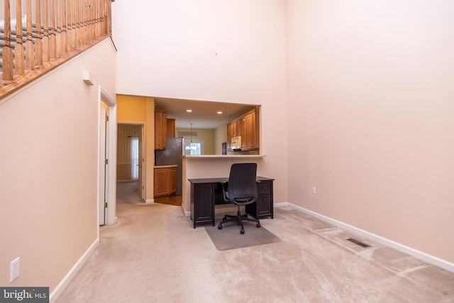 office area featuring light carpet and a towering ceiling