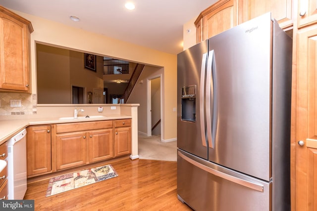 kitchen with dishwasher, backsplash, sink, stainless steel refrigerator with ice dispenser, and light hardwood / wood-style floors