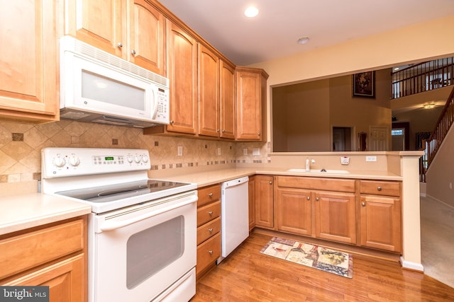 kitchen with backsplash, sink, white appliances, and light wood-type flooring