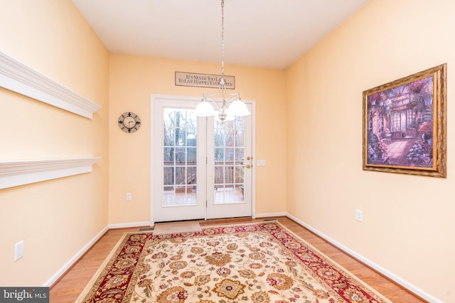 doorway with hardwood / wood-style flooring and an inviting chandelier