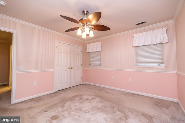 unfurnished bedroom with light carpet, a closet, crown molding, and ceiling fan