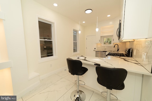 kitchen featuring white cabinetry, kitchen peninsula, light stone counters, and a breakfast bar