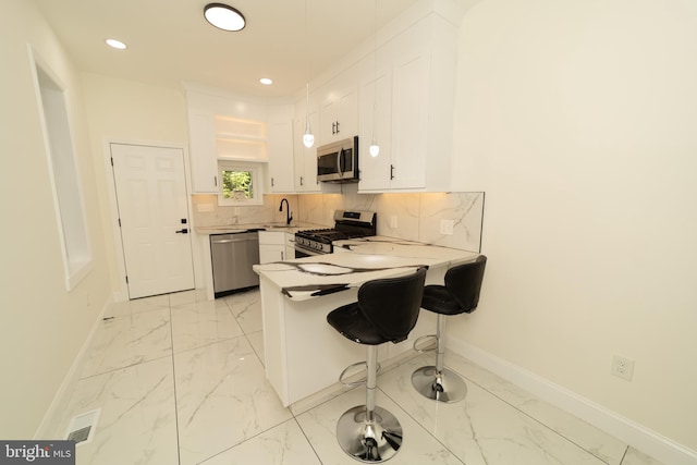 kitchen featuring white cabinetry, appliances with stainless steel finishes, sink, a breakfast bar, and kitchen peninsula