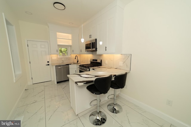 kitchen featuring tasteful backsplash, appliances with stainless steel finishes, a kitchen bar, sink, and white cabinets