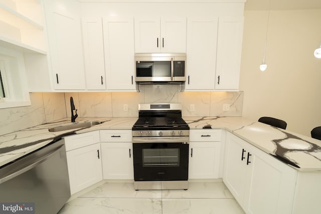 kitchen with white cabinetry, stainless steel appliances, sink, and light stone counters