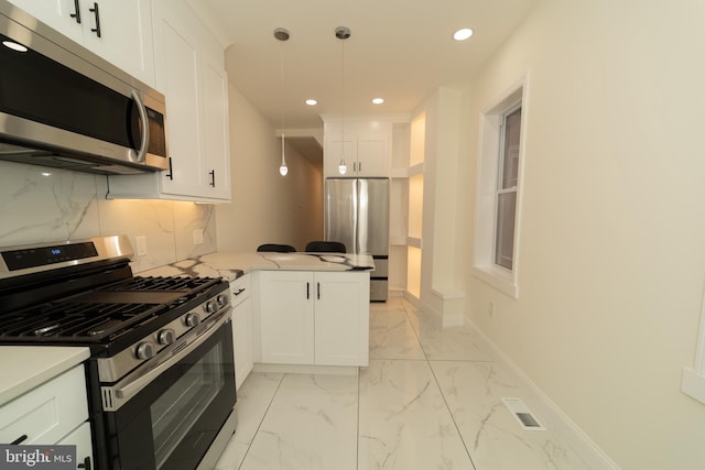 kitchen with appliances with stainless steel finishes, decorative light fixtures, and white cabinets