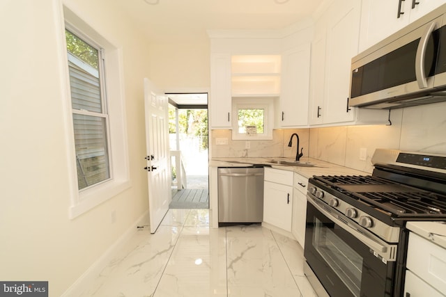 kitchen featuring stainless steel appliances, white cabinets, sink, and backsplash