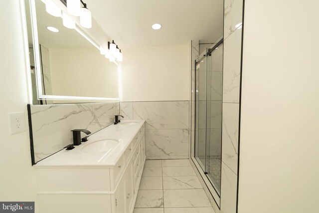 bathroom with a shower with shower door, vanity, and tile walls