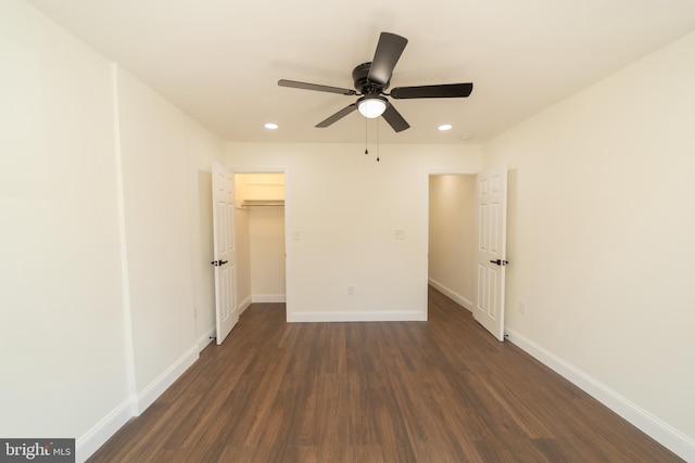 unfurnished bedroom with dark wood-type flooring, ceiling fan, a closet, and a walk in closet