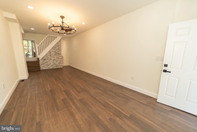 unfurnished room featuring a notable chandelier and dark hardwood / wood-style floors