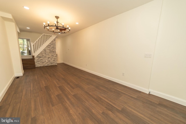 empty room with dark hardwood / wood-style floors and an inviting chandelier