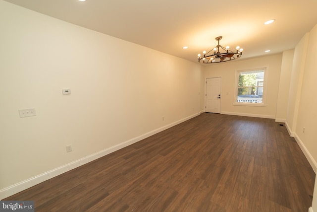 empty room featuring dark hardwood / wood-style floors and a chandelier