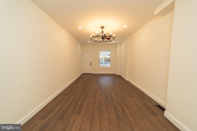 unfurnished room with dark hardwood / wood-style flooring and a notable chandelier