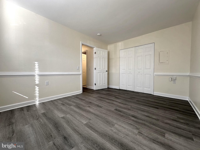 unfurnished bedroom featuring dark wood-type flooring, a closet, and baseboards