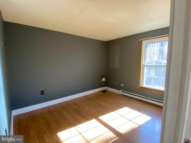 empty room featuring electric panel, a baseboard radiator, and light hardwood / wood-style flooring