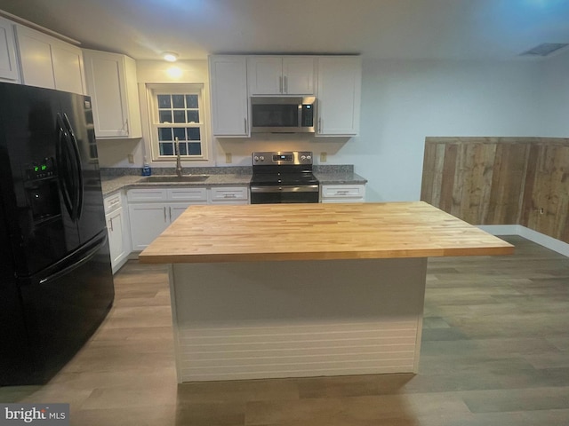 kitchen with white cabinets, wood counters, sink, and appliances with stainless steel finishes