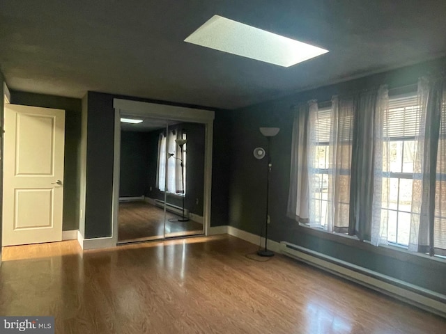 entryway featuring baseboard heating, a skylight, and wood-type flooring