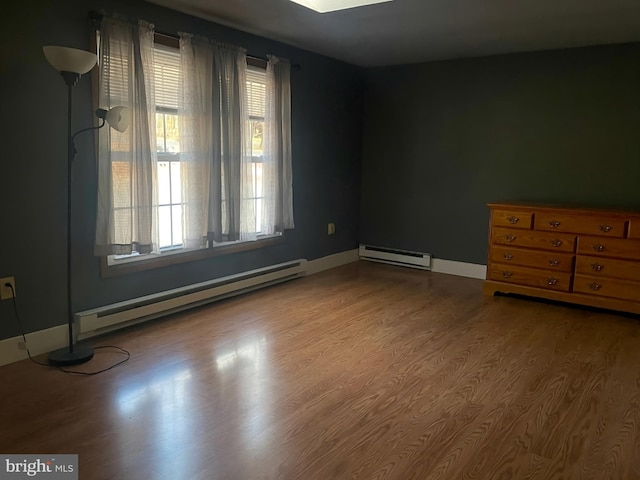 empty room featuring wood-type flooring and a baseboard radiator