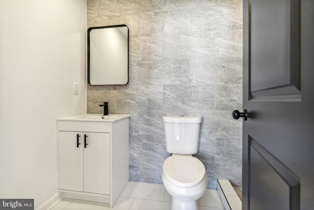 bathroom with tile patterned flooring, vanity, toilet, and tile walls