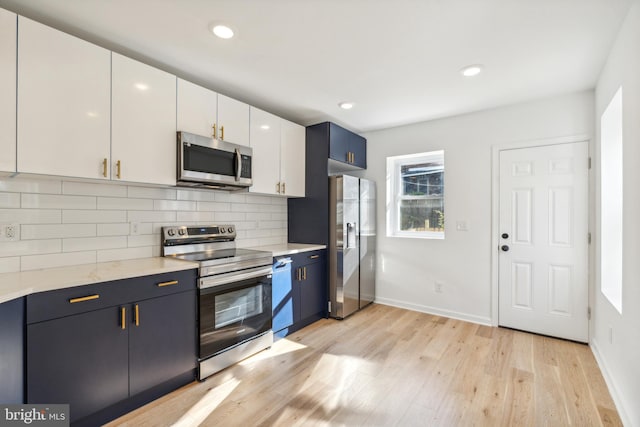 kitchen featuring white cabinetry, appliances with stainless steel finishes, decorative backsplash, blue cabinets, and light hardwood / wood-style flooring