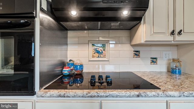 kitchen with decorative backsplash, black electric stovetop, range hood, and light stone counters