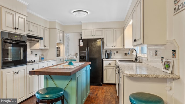 kitchen with black appliances, ornamental molding, a kitchen island, sink, and a kitchen breakfast bar