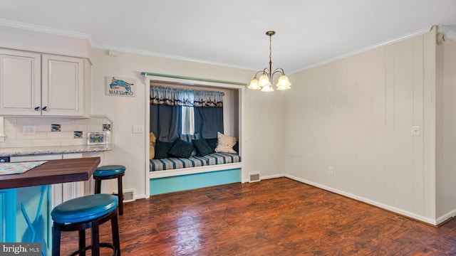 dining area with ornamental molding, dark hardwood / wood-style flooring, and an inviting chandelier