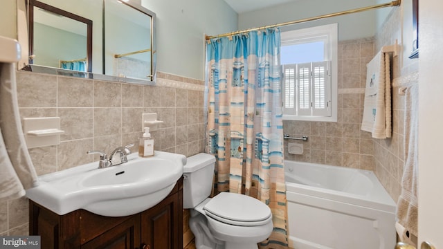 full bathroom with shower / bath combo with shower curtain, vanity, toilet, and tile walls