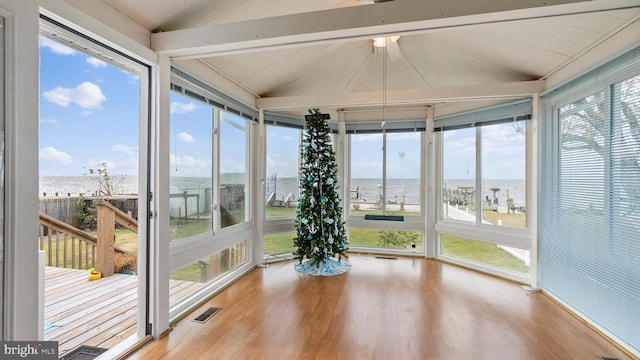 unfurnished sunroom featuring a healthy amount of sunlight, a water view, and vaulted ceiling with beams