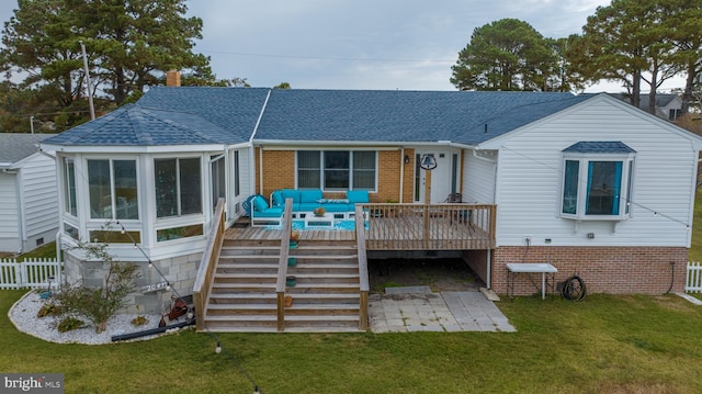 rear view of house featuring a deck, a sunroom, and a yard