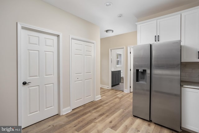 kitchen featuring white cabinets, stainless steel fridge with ice dispenser, light hardwood / wood-style flooring, and backsplash