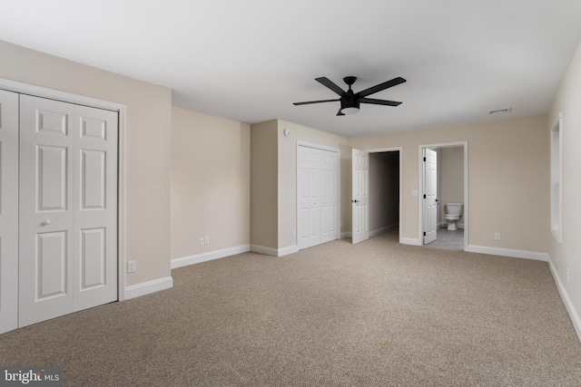 unfurnished bedroom with ceiling fan, ensuite bath, and light colored carpet