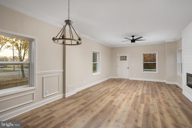 unfurnished living room featuring light hardwood / wood-style flooring, ceiling fan with notable chandelier, and crown molding