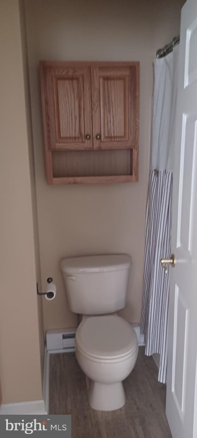 bathroom featuring baseboard heating, toilet, and hardwood / wood-style flooring