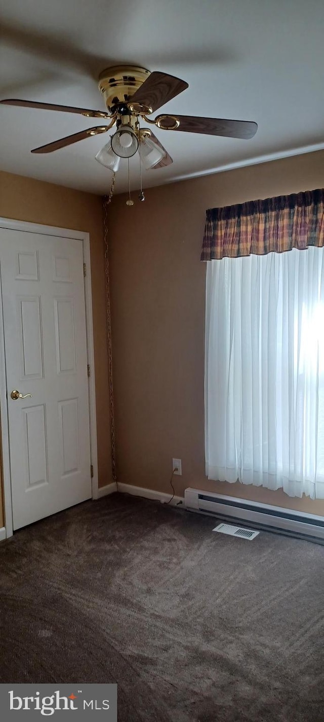 empty room with carpet flooring, a baseboard heating unit, and ceiling fan