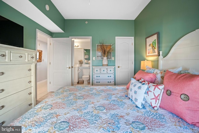 bedroom with ensuite bathroom and light tile patterned floors